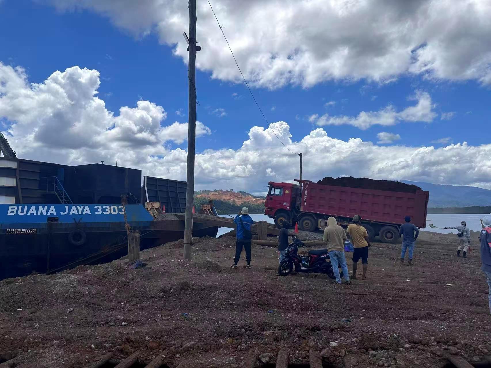Dump truck bermuatan bijih menuju tongkang di area pelabuhan